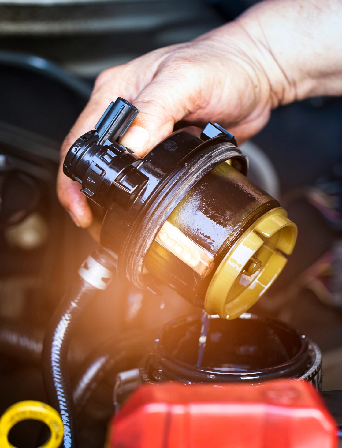 Hand holding car oil filter during maintenance.