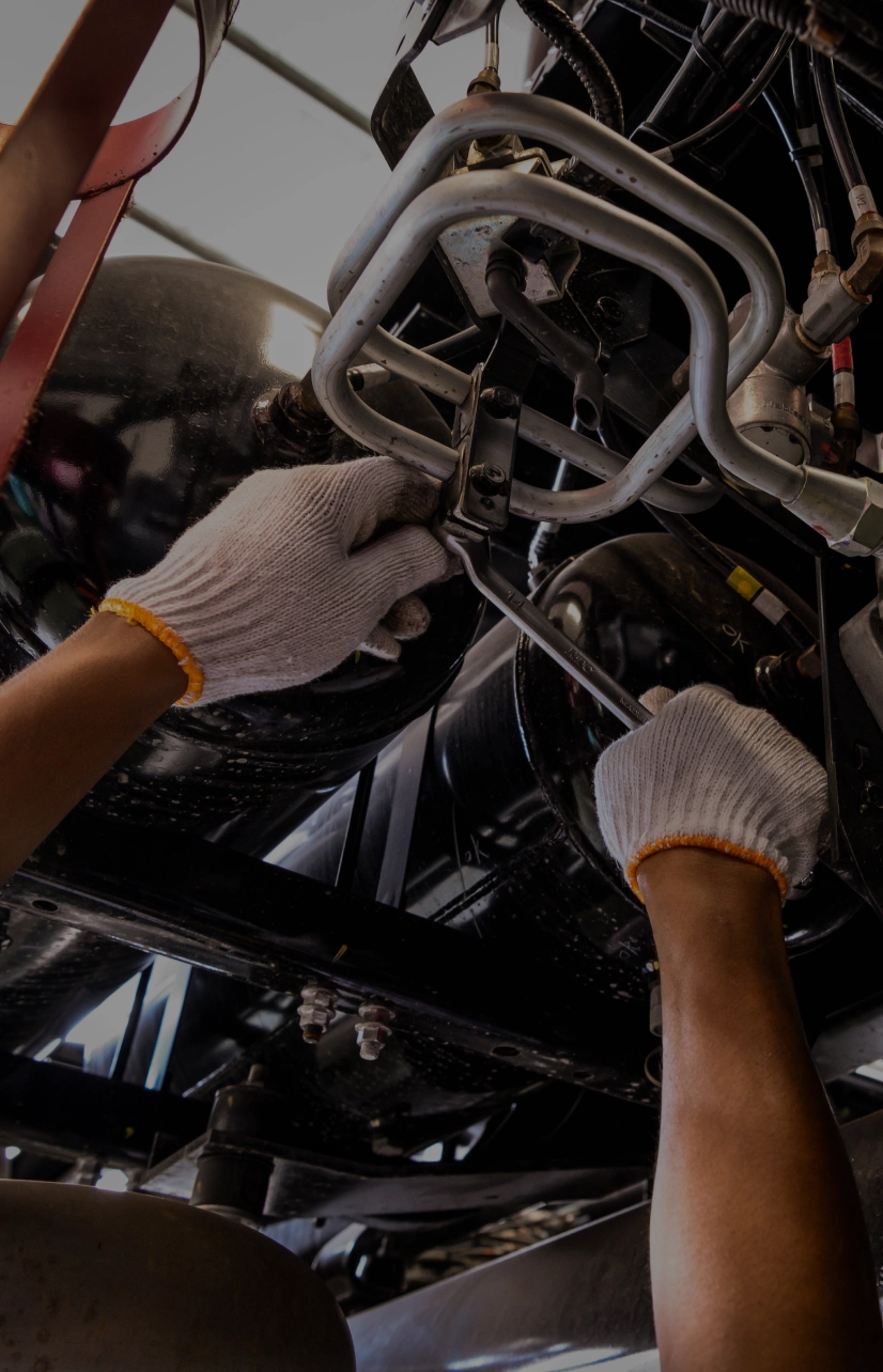 Mechanic working underneath vehicle with tools.