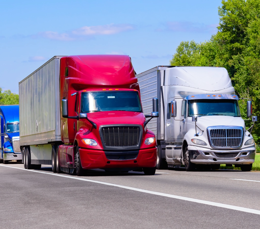 Three trucks driving on a highway.