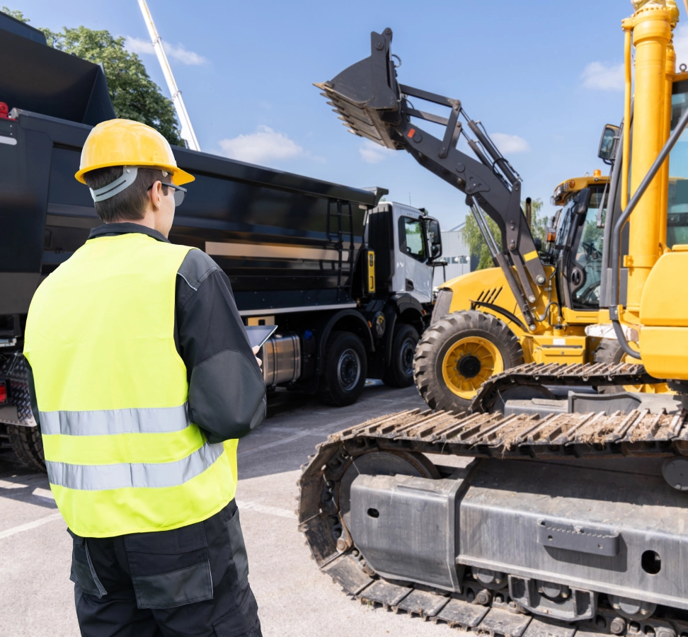 Construction worker observing machinery at worksite.
