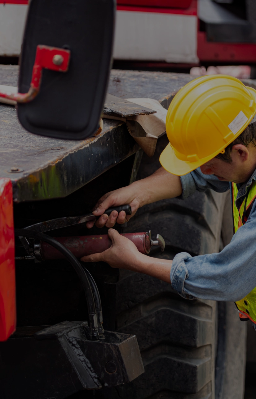 Worker repairing machinery with a grease gun.