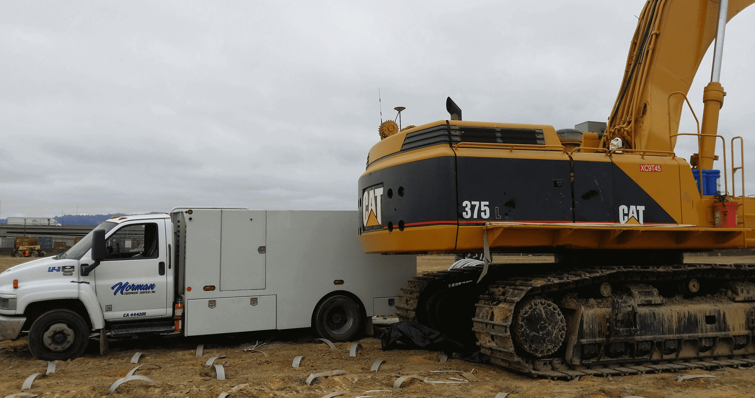 Excavator collides with white utility truck.